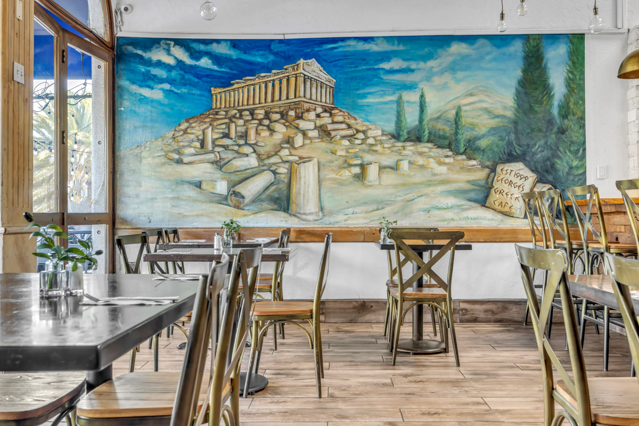 Window-side dining tables beneath the Parthenon mural