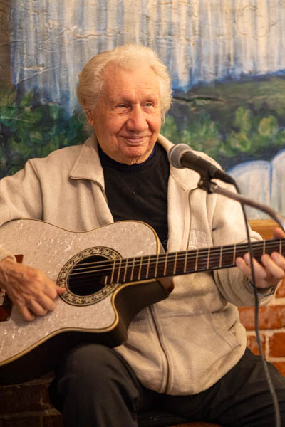 Musician playing guitar inside George’s Greek Cafe